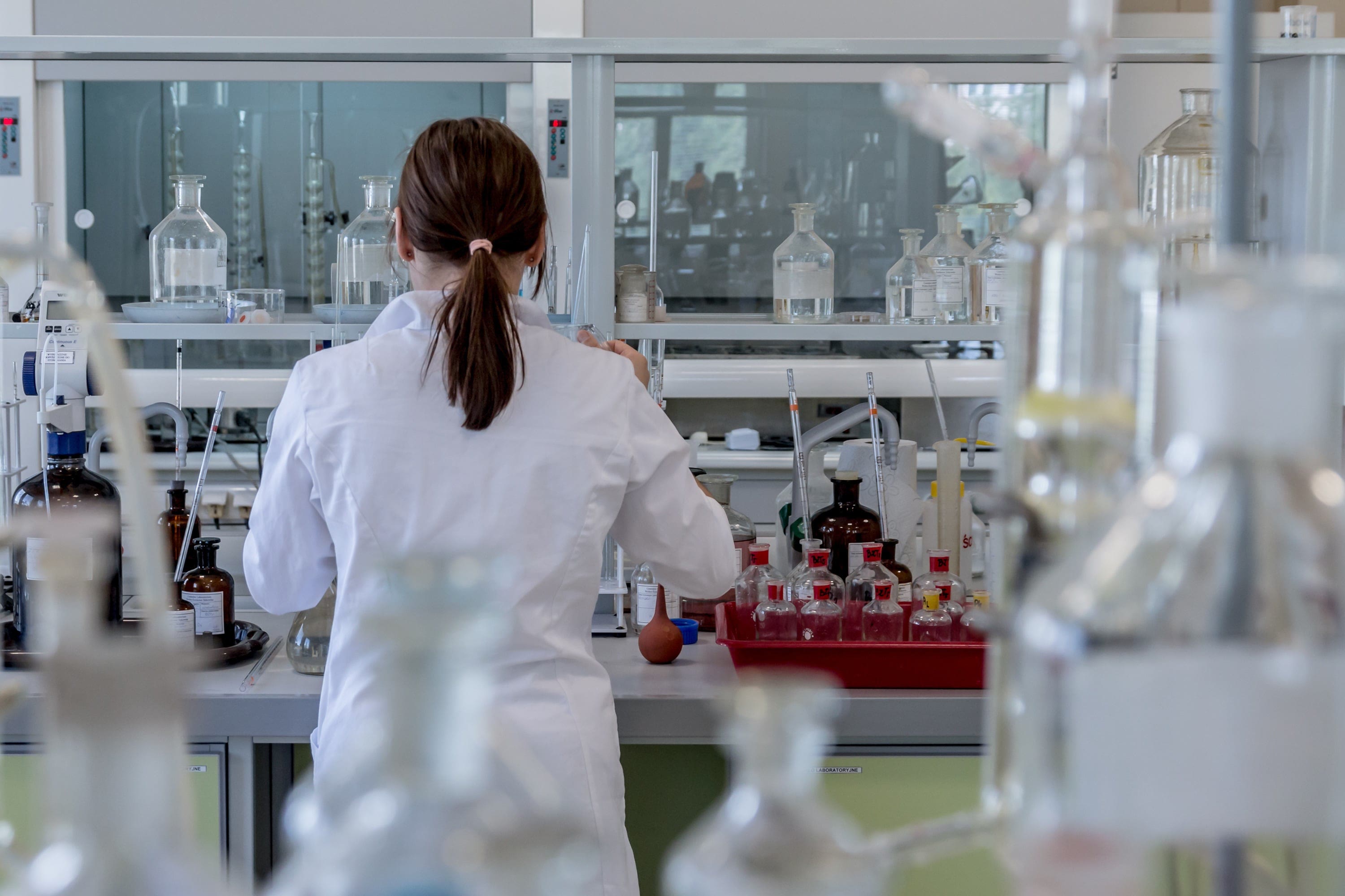 A scientist in a white coat working at a laboratory bench