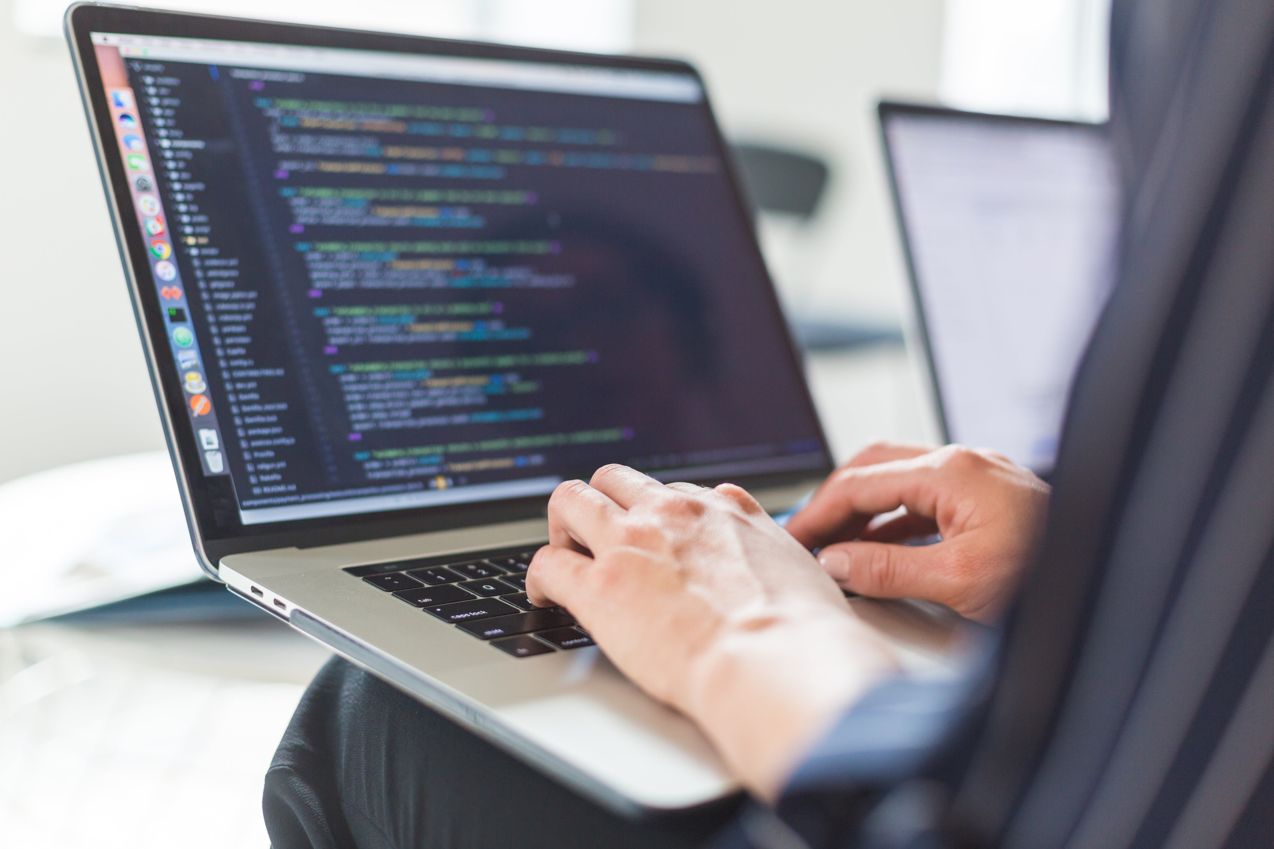 A developer writing code on a laptop