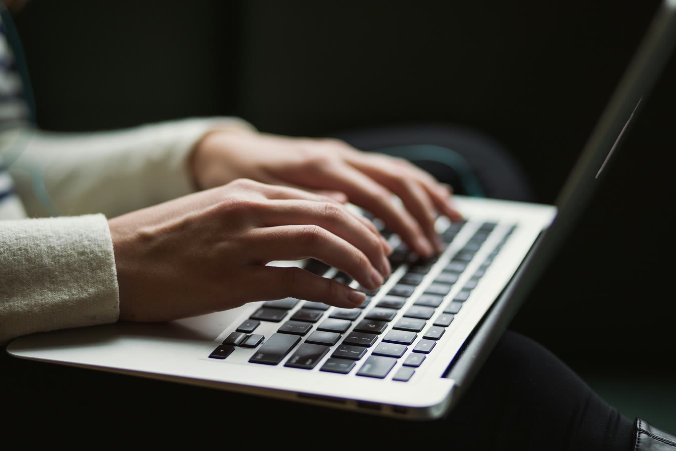 Close-up of hands typing on a laptop keyboard