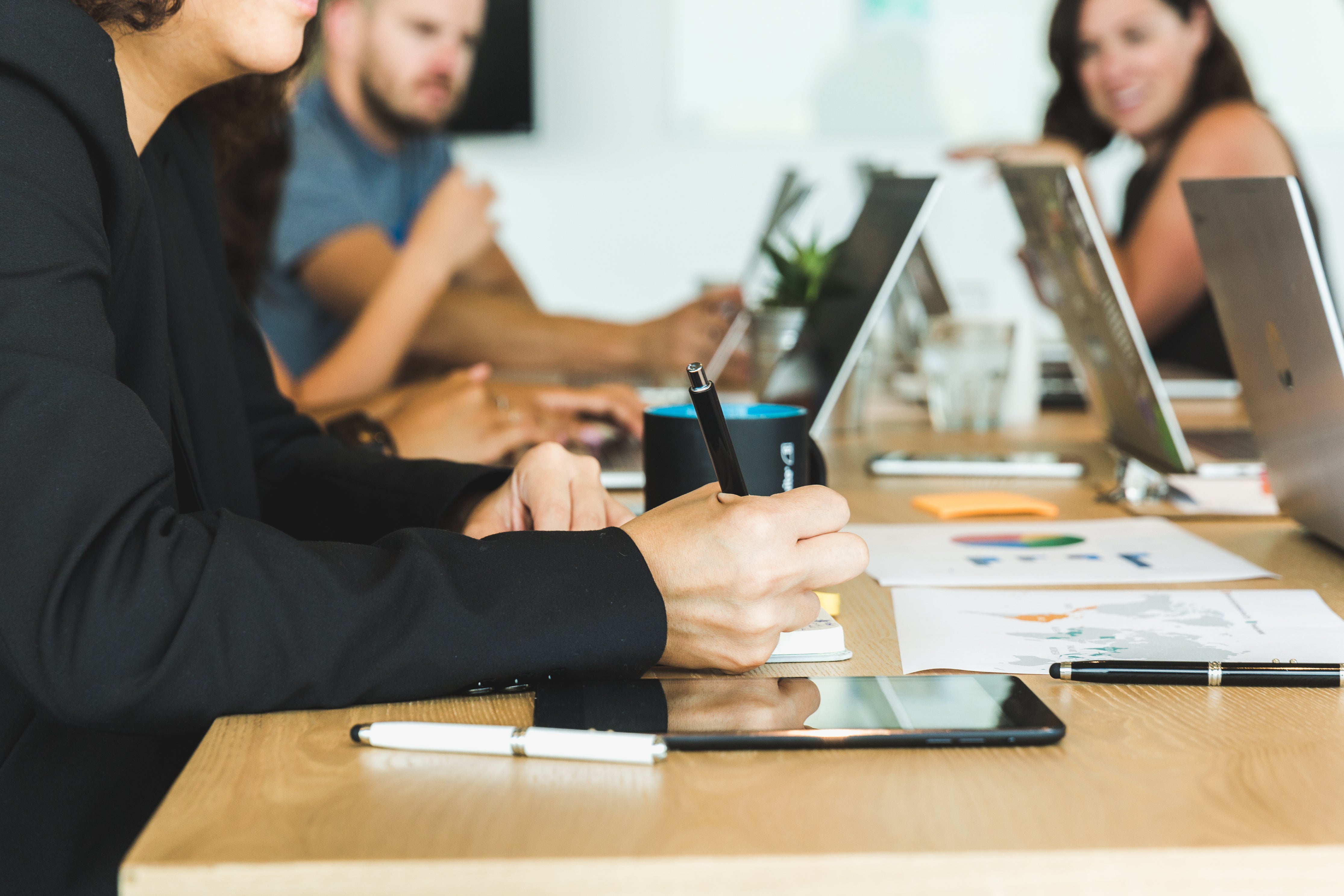 A team working together at a shared table, one person taking notes by hand